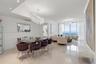 Open-concept interior featuring light-toned polished stone flooring, recessed ceiling lighting, statement crystal chandeliers, and expansive floor-to-