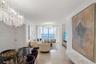 Expansive living area featuring floor-to-ceiling windows with ocean scenery, polished stone flooring, recessed crown molding, and dual crystal chandel