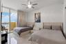 Floor-to-ceiling glass sliding doors opening to a balcony, polished stone flooring, crown molding, and a central ceiling fan with an integrated light 