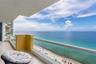 Covered balcony featuring polished stone flooring, glass panel railings, and expansive oceanfront scenery