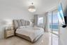 Polished tile flooring, floor-to-ceiling glass paneling, balcony access, and an ornate drum-style chandelier