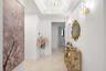 Foyer featuring a recessed tray ceiling, tiered crystal chandelier, wall-mounted crystal sconces, and neutral stone-finish flooring