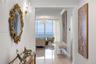 Entryway featuring polished stone-finish flooring, crown molding, and crystal wall-mounted light fixtures, leading to floor-to-ceiling windows with oc
