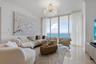 Floor-to-ceiling windows featuring ocean panoramas, polished tile flooring, and a tiered crystal chandelier