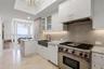 Chef’s kitchen featuring custom white cabinetry, stone slab backsplash, farmhouse-style apron sink, professional-grade stainless steel range, and ston