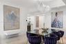 Statement chandelier with crystal accents, polished stone flooring, and a built-in wet bar featuring cabinetry, glass shelving, and a beverage refrige