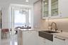 Custom kitchen featuring white cabinetry with glass-front uppers, stone-surround backsplash, farmhouse sink with bronze-tone hardware, and light-refle