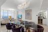 Open-concept space featuring floor-to-ceiling glass, custom crystal chandeliers, polished stone flooring, and a built-in wet bar with a glass-front be