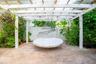 Outdoor patio featuring a white pergola structure, paver flooring, and privacy fencing