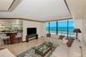 Living area featuring gorgeous ocean views, a custom wood-finished wet bar, stone tile flooring, crown molding, recessed lighting, and expansive floor