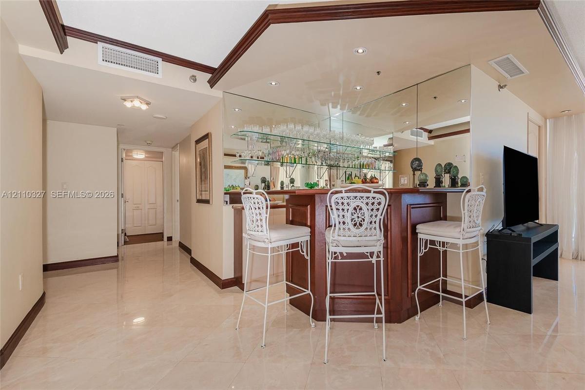 Dining area featuring recessed ceiling detail, crown molding, stone-finish flooring, and a multi-arm chandelier