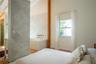 Vaulted ceiling, stone-tiled privacy wall, deep-soaking tub with wall-mounted plumbing, natural wood-finish flooring, and exposed vertical wood struct