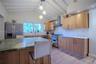 Kitchen featuring a vaulted ceiling with exposed beams, natural wood-finish cabinetry, a stone-surfaced kitchen island, stainless steel appliances, an