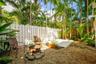 Private backyard featuring a white privacy fence, gravel ground cover, elevated wood deck, and mature palm trees