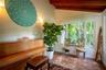 Exposed wooden ceiling beams, large picture windows, brick-style floor tiles, and painted white brick wall accents