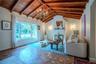 Vaulted ceiling with exposed wood beams, terracotta hexagonal floor tiling, central chandelier, and a masonry fireplace with decorative tile surround