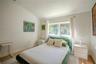 Vaulted ceiling featuring neutral wall paint, wood-finish flooring, and a window with a curtain rod assembly
