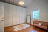Floor-to-ceiling built-in cabinetry, vaulted ceiling with exposed beams, wood-finish flooring, and single-pane window with roller shade