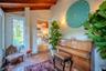 Vaulted ceilings with exposed wooden beams, terracotta tile flooring, painted brick wall, and wall-mounted sconce lighting