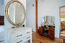 White vanity featuring an integrated basin, stone countertop, and polished hardware, complemented by a large oval mirror with an ornate metal frame, s
