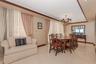 Curved architectural wall feature, polished stone-finish tile flooring, custom tiered wood crown molding, and ornate multi-arm chandelier