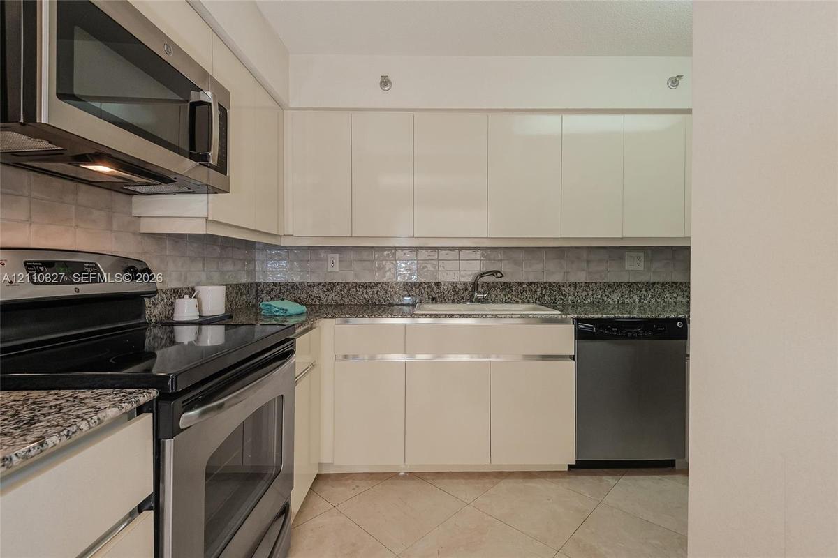 Kitchen featuring flat-panel cabinetry, stone countertops, stainless steel side-by-side refrigerator, recessed lighting, and tile flooring