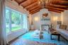 Vaulted ceiling with exposed wood beams, fireplace featuring decorative tile surround, terracotta tile flooring, and oversized windows