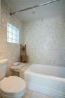 Bathroom featuring terrazzo-style wall and deck tile, a built-in stone ledge, and glass block window