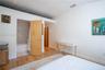 Wood-finish flooring, light wood interior door, and bathroom featuring a tub-shower combination with textured wall tiling