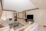 Custom wood-finish wet bar with a mirrored backsplash, glass shelving, recessed lighting, and tile flooring
