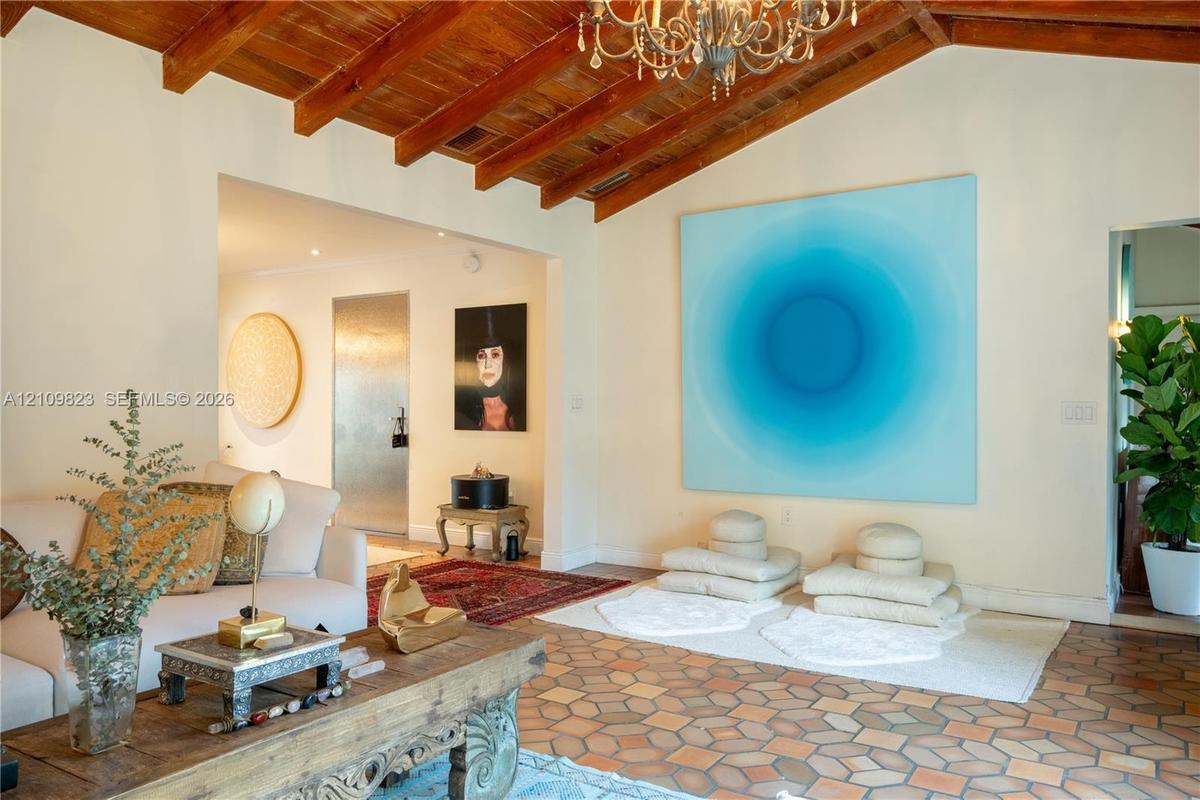 Vaulted ceilings with exposed wooden beams, hexagon-patterned terra cotta tile flooring, and decorative multi-arm chandelier