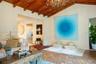 Vaulted ceilings with exposed wooden beams, hexagon-patterned terra cotta tile flooring, and decorative multi-arm chandelier