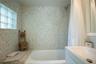 Bathroom featuring terrazzo wall tiles, a built-in tub surround, a glass block window, and a wall-mounted shower head