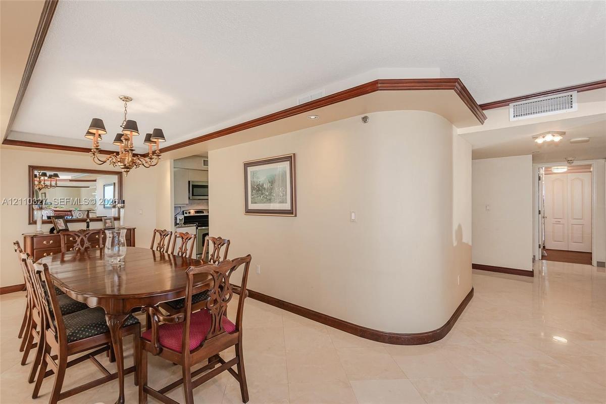 Dining area featuring an ornate multi-arm chandelier, built-in wet bar with mirrored backsplash, and floor-to-ceiling sliding glass doors opening to a