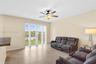 Large-format tile flooring, ceiling fan with integrated lighting, and glass sliding doors