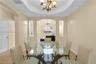 Dining space featuring a tiered tray ceiling, recessed wall niches, tile flooring, and an ornamental chandelier