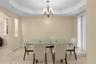 Tray ceiling with multi-arm chandelier, stone flooring, and built-in wall niche