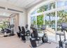 Fitness center featuring floor-to-ceiling arched windows, high-contrast light walls, and commercial-grade carpet tile flooring
