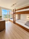 Floor-to-ceiling glass sliding door with balcony access, wood-finish flooring, crown molding, track lighting, and wall-mounted sconces