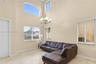 Two-story vaulted ceiling featuring a multi-light chandelier, arched accent window, stone flooring, and large picture windows