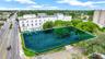 Corner lot featuring a paved surface parking area, perimeter landscaping, mature trees, and direct street access