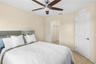 Room featuring tile flooring, a mirrored headboard accent, a six-blade ceiling fan with integrated lighting, and a six-panel interior door