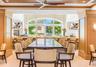 Custom wood-paneled walls and ceiling, large arched window, built-in service bar with stone countertop, ceiling fan with wood-finish blades, and reces