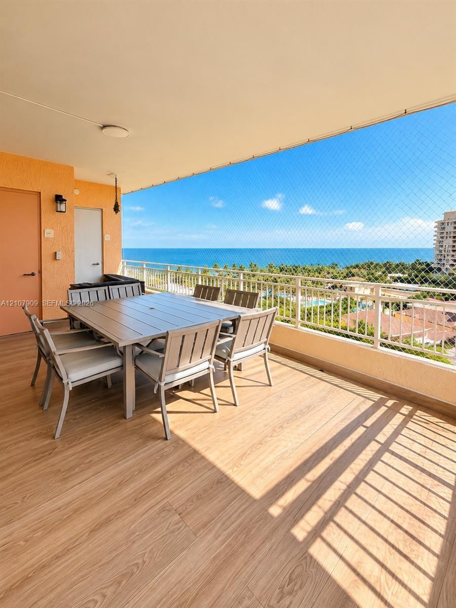 Covered balcony featuring wood-finish flooring, metal railing, and ocean scenery