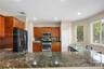 Kitchen featuring stained wood cabinetry, stone-surface breakfast bar, stainless steel appliances, and natural lighting