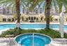 Outdoor swimming pool with multiple lanes, stone-tiled spa, and mature palm trees