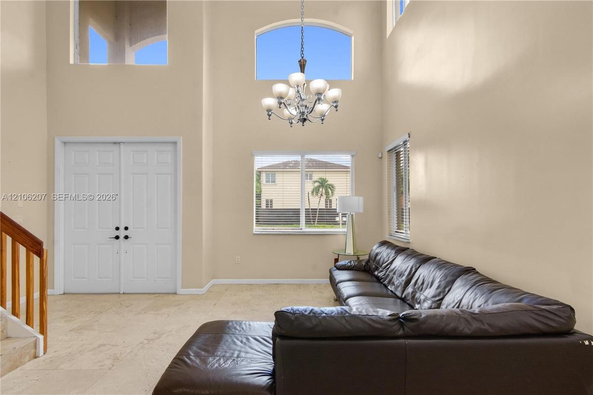 Double-height ceilings, arched transom windows, tile flooring, multi-light chandelier, and double-door entry