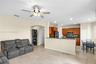 Open floor plan featuring stone-style tile flooring, wood cabinetry, stone countertops, recessed lighting, and a ceiling fan