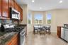 Kitchen featuring wood cabinetry, stone countertops, stainless steel gas range, built-in microwave, and tile flooring