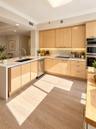 Kitchen featuring light-finish cabinetry, white countertops with an integrated waterfall edge, wood-finish flooring, undermount sink with a gooseneck 